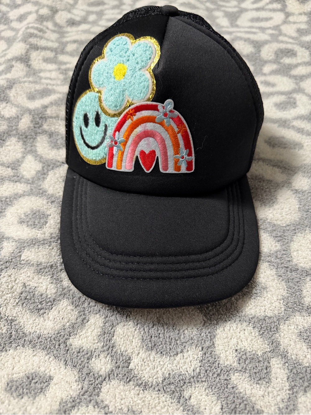 Black womenโs Trucker Hat with Rainbow & Flower Patches